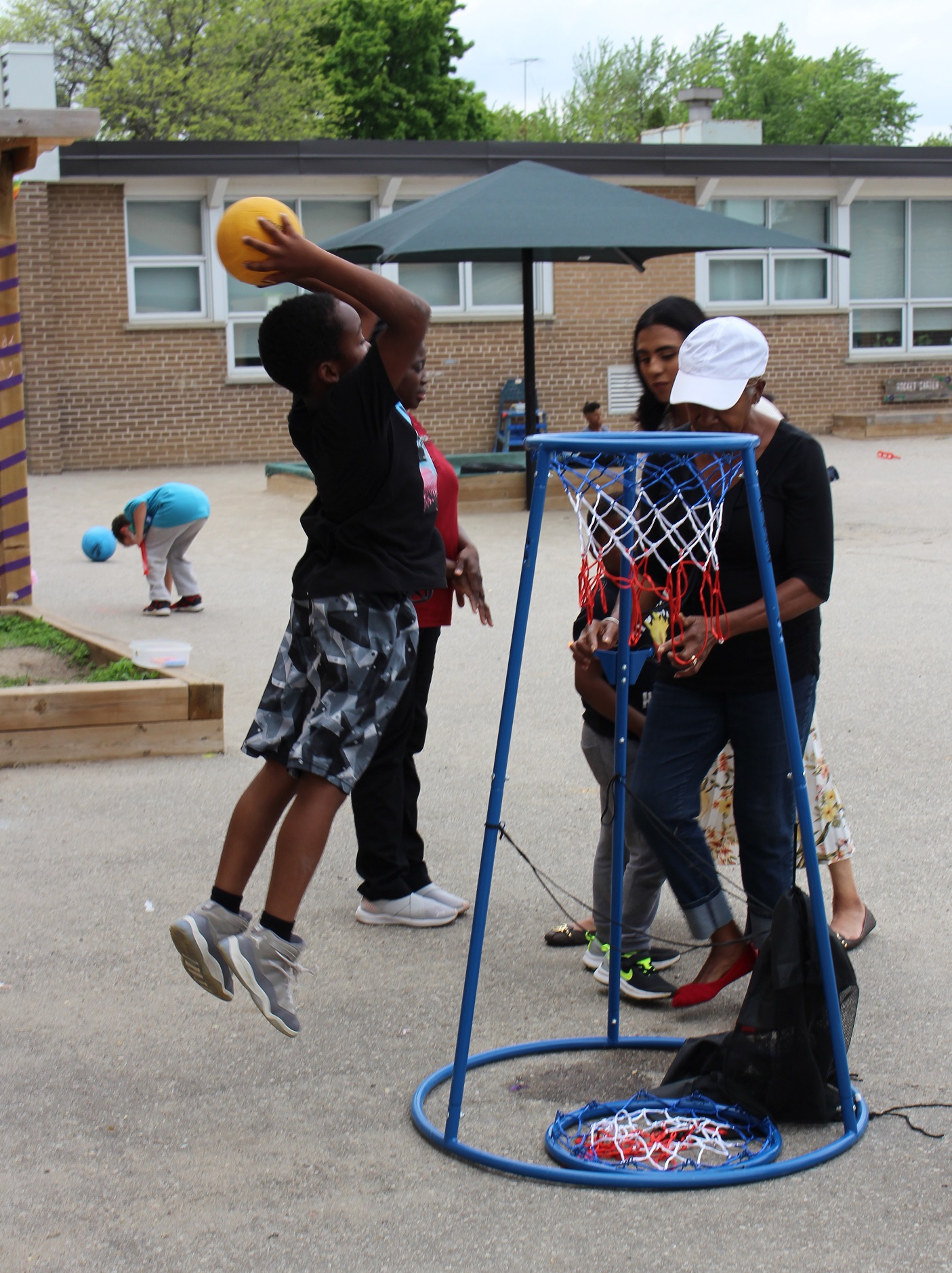 A child makes a slam dunk with a basketball outside at a PLASP program