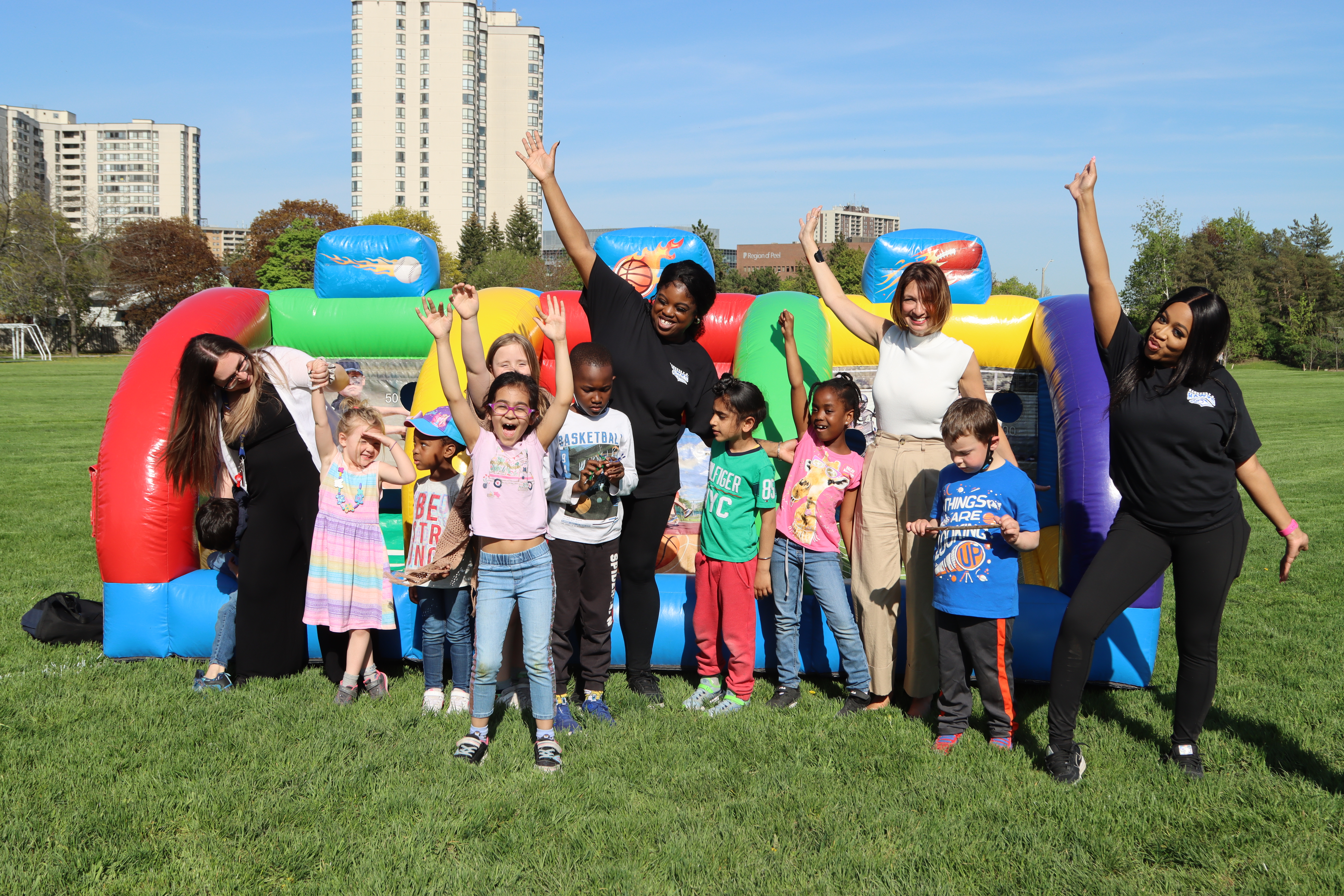 PLASP children and educators pose in front of a bouncy castle in a field, smiling for the camera