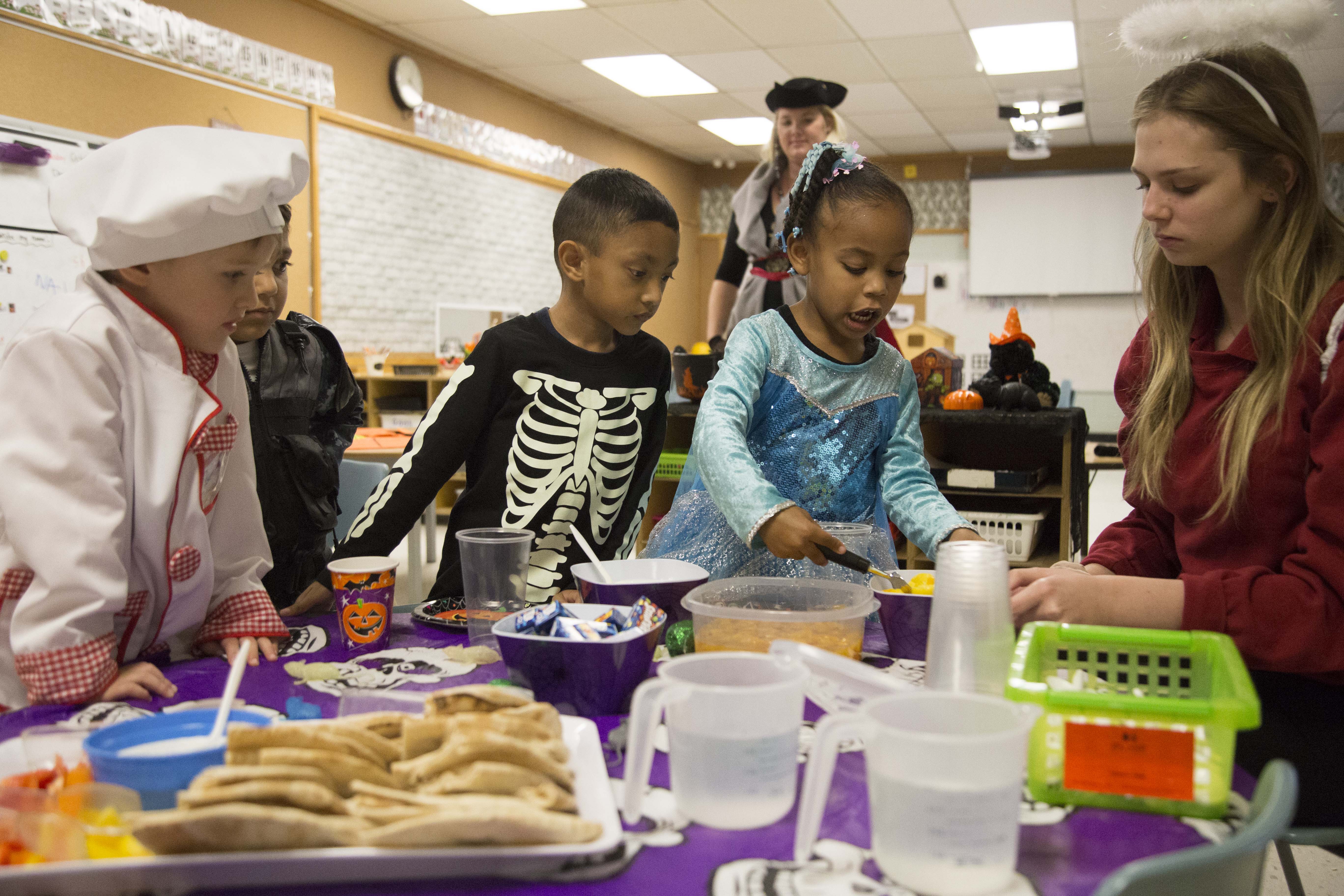 A group of PLASP children stand around a snack table, waiting their turn to enjoy a healthy snack
