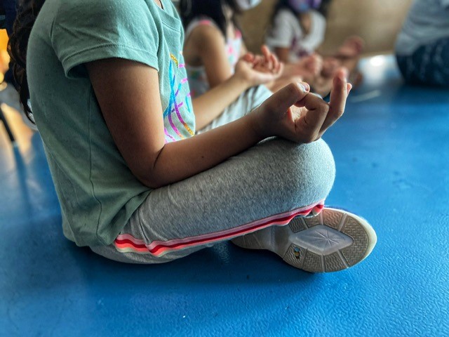 A close up of a child's hand, who is in a yoga pose