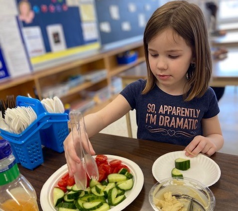 A girl serves herself a healthy snack of vegetables in a PLASP program